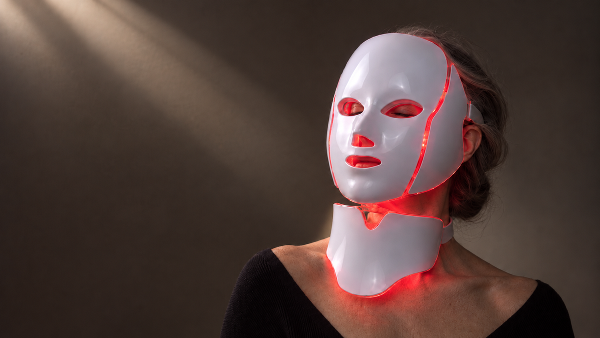 Woman wearing the CÉVANNE LED and microcurrent face and neck mask, lit in red